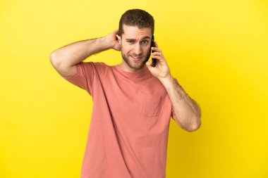 Soyutlanmış bir arkaplanda cep telefonu kullanan yakışıklı sarışın adamın şüpheleri var.