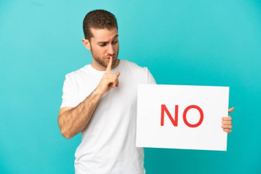 Yakışıklı sarışın, izole edilmiş mavi arka plan. Elinde yazılı bir afiş var. Sessizlik hareketi yapmıyor.