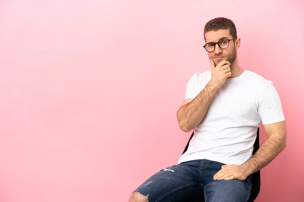 Mladý Muž Sedí Židli Nad Izolované Růžové Pozadí Myšlení — Stock fotografie