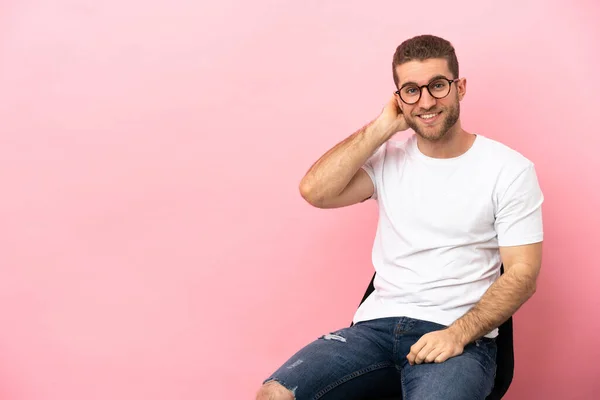 Jongeman Zit Een Stoel Geïsoleerde Roze Achtergrond Lachen — Stockfoto