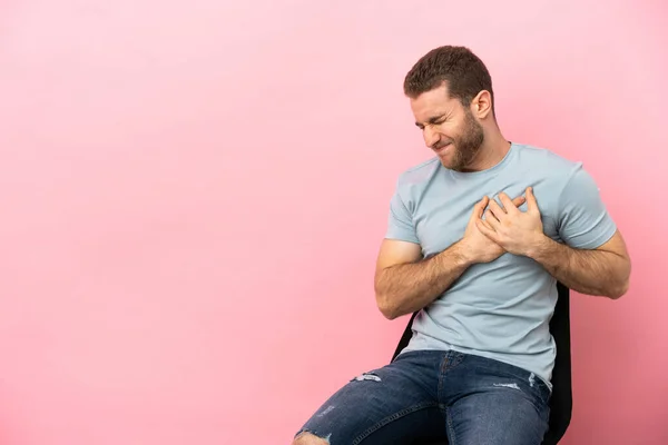 Young Man Sitting Chair Isolated Pink Background Having Pain Heart —  Fotos de Stock