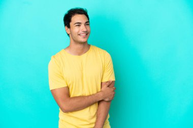 Kafkasyalı yakışıklı adam soyutlanmış mavi arka planda gülüyor.