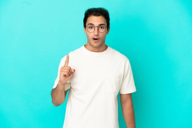 Izole mavi arka plan üzerinde Kafkas yakışıklı adam bir parmak kaldırırken çözüm gerçekleştirmek niyetinde