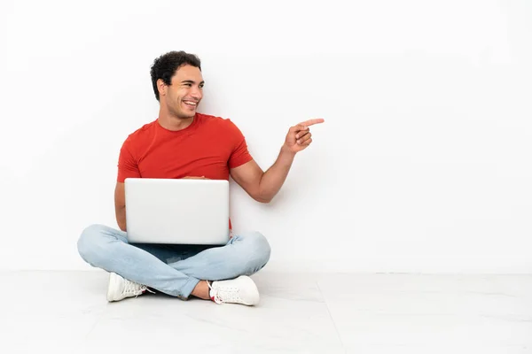 Caucasian Handsome Man Laptop Sitting Floor Pointing Finger Side Presenting — Foto Stock