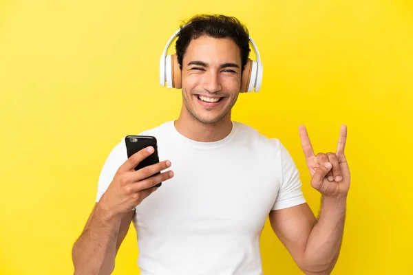 Caucasian Handsome Man Isolated Yellow Background Listening Music Mobile Making — Φωτογραφία Αρχείου