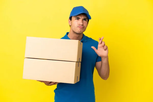Delivery Man Isolated Yellow Wall Fingers Crossing Wishing Best — Stock Photo, Image