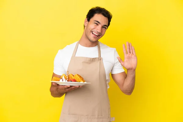 Restaurant Waiter Holding Waffles Isolated Yellow Background Saluting Hand Happy — Photo