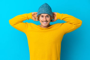 Yakışıklı sarışın adam mavi arka planda tek başına gülüyor.