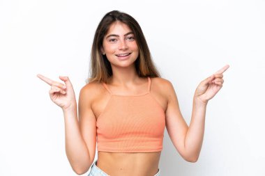 Beyaz arka planda izole edilmiş genç beyaz kadın parmak uçlarını işaret ediyor ve mutlu.