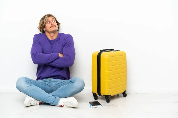 Young Blonde Man Suitcase Sitting Floor Making Doubts Gesture While — Fotografia de Stock