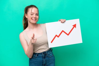 Yeşil arka planda izole edilmiş genç beyaz bir kadın elinde büyüyen bir istatistik okunun sembolü olan ve ön tarafı işaret eden bir tabela tutuyor.