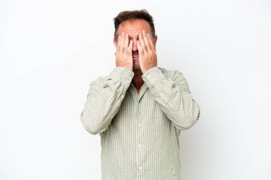Beyaz arka planda izole edilmiş orta yaşlı beyaz bir adam gözlerini elleriyle kapatıyor.