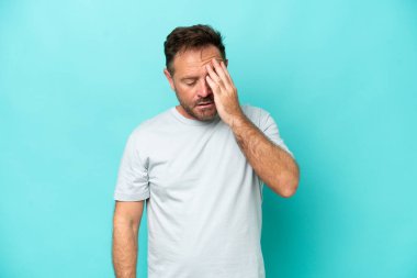 Kafkasyalı orta yaşlı bir adam mavi arka planda baş ağrısı ile izole edilmiş.