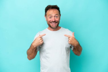 Mavi arka planda izole edilmiş orta yaşlı beyaz bir adam baş parmak işareti yapıyor.
