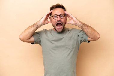 Beyaz tenli orta yaşlı bir adam bej arka planda, sürpriz bir ifadeyle izole edilmiş.