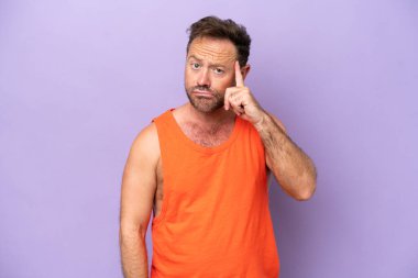Orta yaşlı beyaz bir adam mor arka planda izole edilmiş bir fikir düşünüyor.