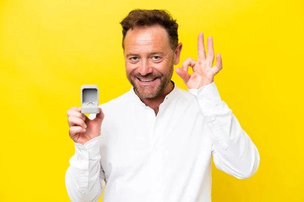 Middle Age Man Holding Engagement Ring Isolated Yellow Background Showing — Stok fotoğraf