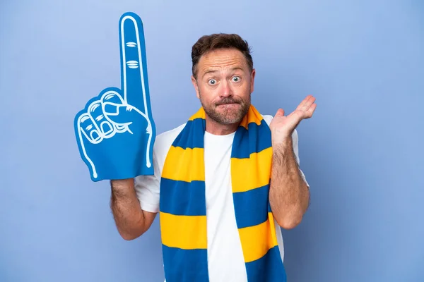 Middle age caucasian sports fan man isolated on blue background having doubts while raising hands