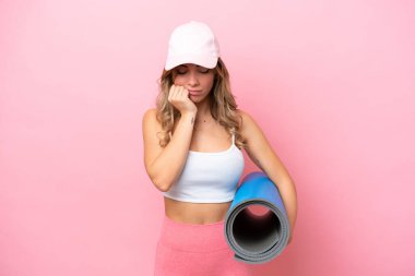 Genç sporcu kadın, elinde minder tutarken yoga derslerine gidiyor.