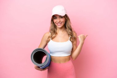 Genç sporcu kadın yoga derslerine giderken elinde bir hasırla ürünü sunuyor.