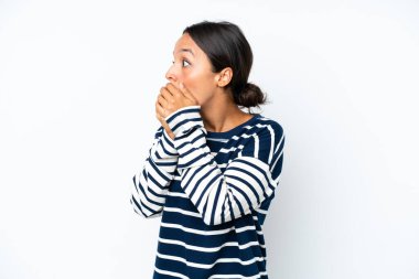 Young hispanic woman isolated on white background covering mouth and looking to the side