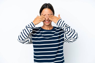 Young hispanic woman isolated on white background covering eyes by hands and smiling