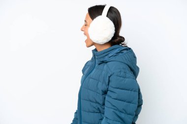 Young hispanic woman wearing a winter earmuffs isolated on white background laughing in lateral position