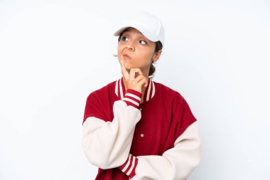 Young hispanic woman wearing a baseball uniform isolated on white background having doubts while looking up