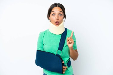 Young hispanic woman wearing a neck brace and sling isolated on white background intending to realizes the solution while lifting a finger up