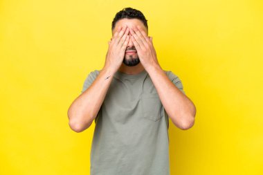 Young Arab handsome man isolated on yellow background covering eyes by hands