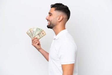 Young Arab man taking a lot of money isolated on white background laughing in lateral position