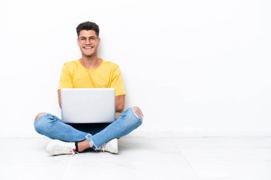 Young man sitting on the floor isolated on white background keeping the arms crossed in frontal position