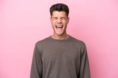 Pembe arka planda izole edilmiş genç beyaz bir adam ağzı açık bir şekilde öne doğru bağırıyor.