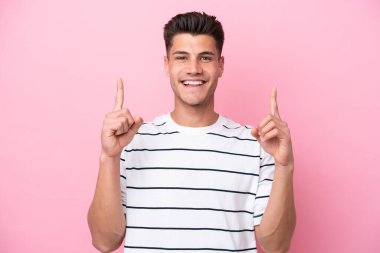 Pembe arka planda izole edilmiş genç beyaz adam harika bir fikre işaret ediyor.