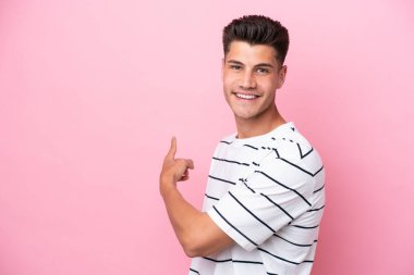 Pembe arka planda izole edilmiş genç beyaz adam geriye bakıyor.