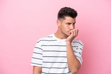 Pembe arka planda izole edilmiş genç beyaz adamın şüpheleri var.