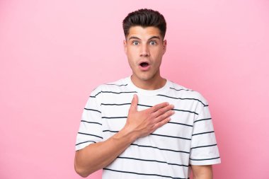 Pembe arka planda izole edilmiş genç beyaz adam sağa bakarken şaşırdı ve şok oldu.