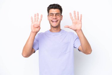 Beyaz arka planda izole edilmiş beyaz tenli genç dokuz parmaklı sayıyor.