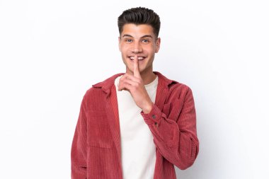 Beyaz arka planda izole edilmiş genç beyaz bir adam sessizlik işareti gösteriyor. Parmağını ağzına sokuyor.