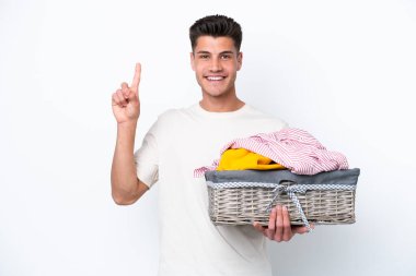Young caucasian man holding laundry basket isolated on white background pointing up a great idea