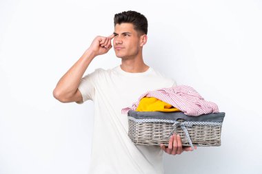 Young caucasian man holding laundry basket isolated on white background having doubts and thinking