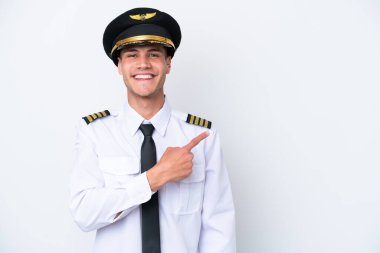 Beyaz arka planda izole edilmiş Kafkasyalı uçak pilotu bir ürün sunmak için kenarı işaret ediyor