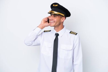 Beyaz arka planda izole edilmiş Kafkasyalı uçak pilotu cep telefonuyla birileriyle sohbet ediyor.