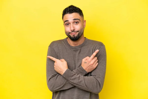 Young Arab Handsome Man Isolated Yellow Background Pointing Laterals Having — Stockfoto