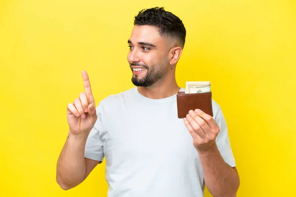 Young Arab Man Holding Wallet Isolated Yellow Background Intending Realizes — стоковое фото