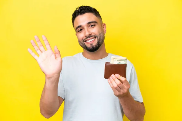 Young Arab Man Holding Wallet Isolated Yellow Background Saluting Hand — 图库照片