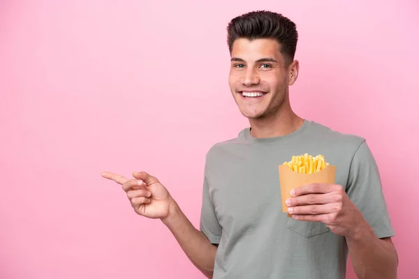 Young Caucasian Man Holding Fried Chips Isolated Pink Background Pointing — Stockfoto