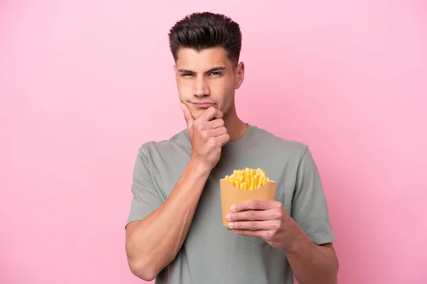 Young Caucasian Man Holding Fried Chips Isolated Pink Background Thinking — Stockfoto