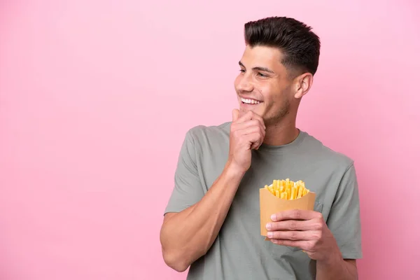 Young Caucasian Man Holding Fried Chips Isolated Pink Background Looking — Stockfoto