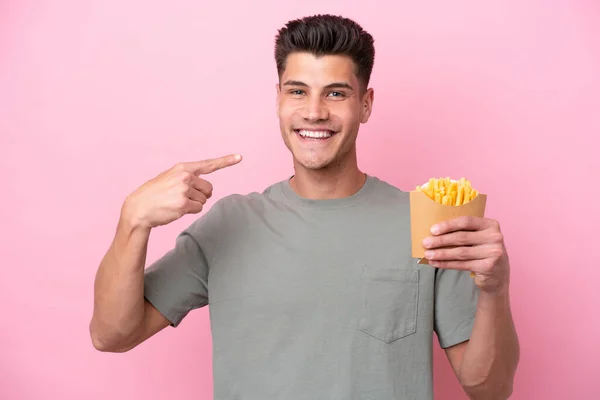 Young Caucasian Man Holding Fried Chips Isolated Pink Background Giving — Stockfoto